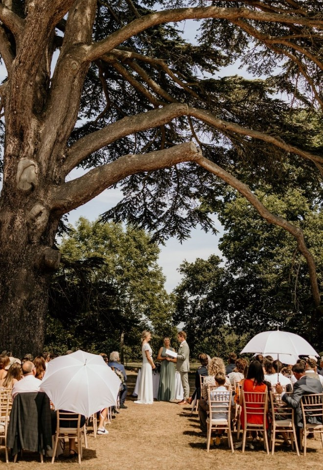 Bride and groom standing underneath tree outside Glewstone Court Country House in Herefordshire