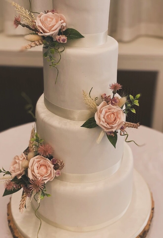 four tier iced wedding cake decorated with faux flowers 