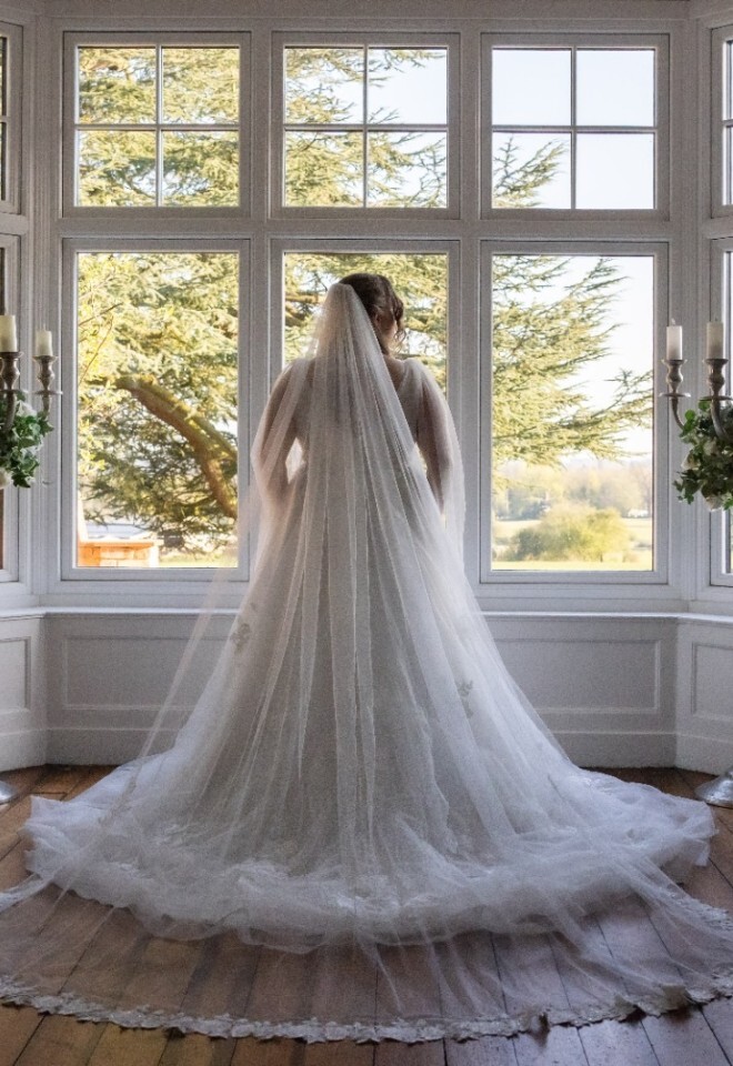 A bride standing in front of a grand window area in a Warwickshire country wedding venue