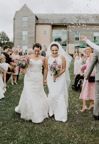 Brides after getting married having confetti moment outside De Vere Cotswold Waterpark hotel