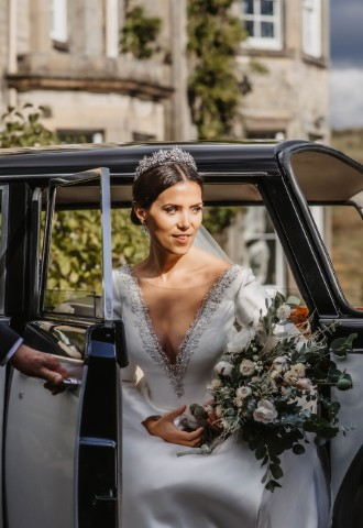 Bride exiting wedding car at Auchen Castle - a romantic castle wedding venue in Scotland