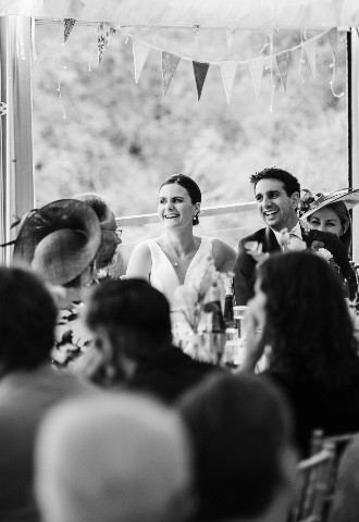 Bride and groom laughing during bridesmaids speech 