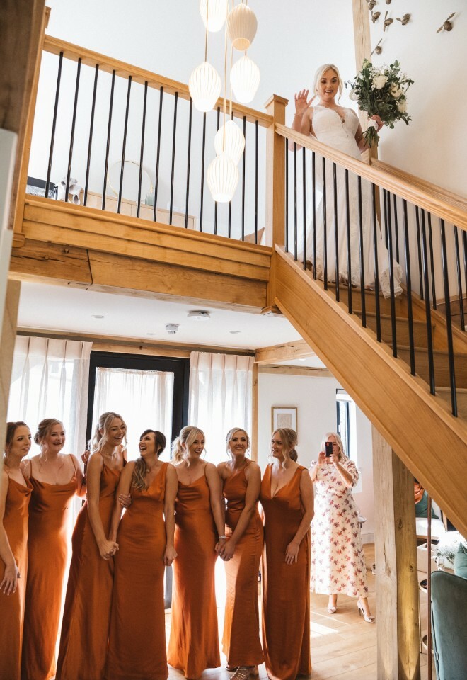 Bride descends the stairs inside Lavender Lodge to reveal her bridal look to her Bridesmaids