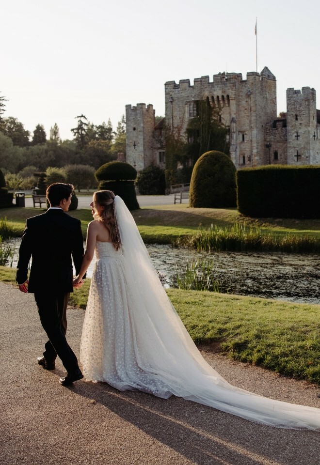 Bride and groom walk next to Hever Castle