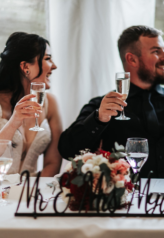 Bride and groom raising a glass during the wedding speeches in the marquee at The Cock O’Barton