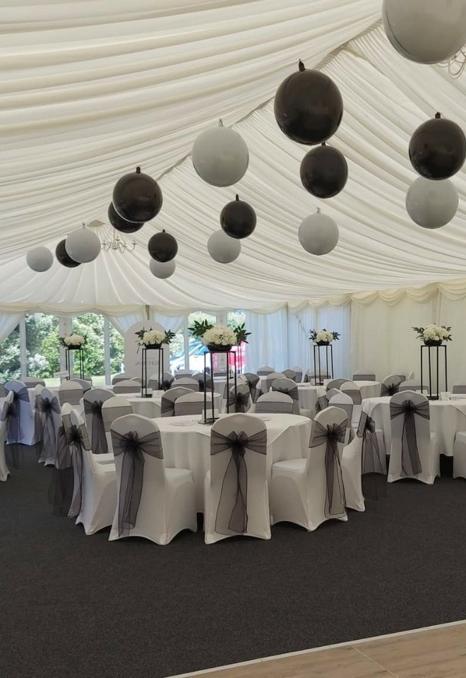 marquee with black & white balloons, white chair covers & black sashes from inflate 2 create