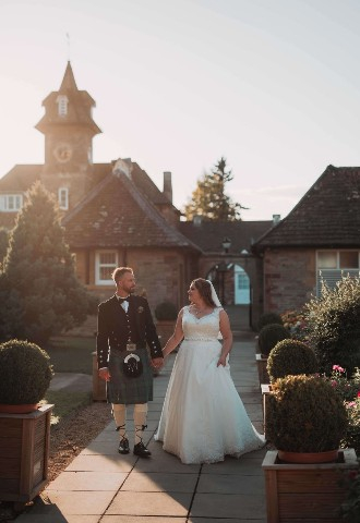 Groom in a kilt & bride just married in the courtyard at Eastwood Park, Gloucestershire