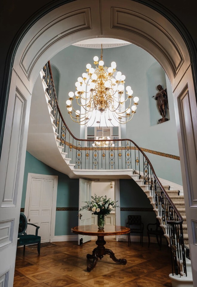 Grand staircase and chandelier inside Henlade House wedding venue in Somerset, creating a striking ceremony and photo backdrop