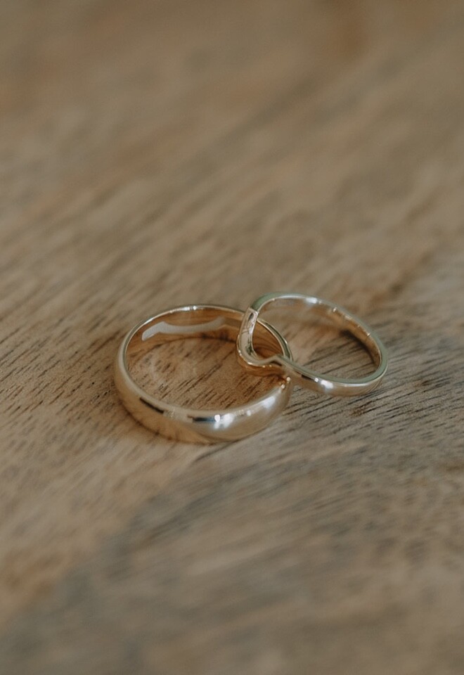 A shaped womens wedding ring with an engraved mens wedding ring in gold