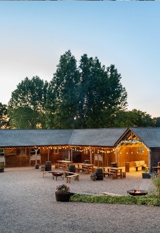 Manor Hill House stunning barn in an evening setting decorated with lights, rustic tables, and fire pits
