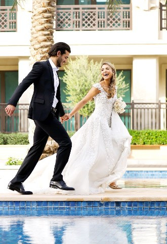 Bride and groom holding hands by the Palace Downtown pool