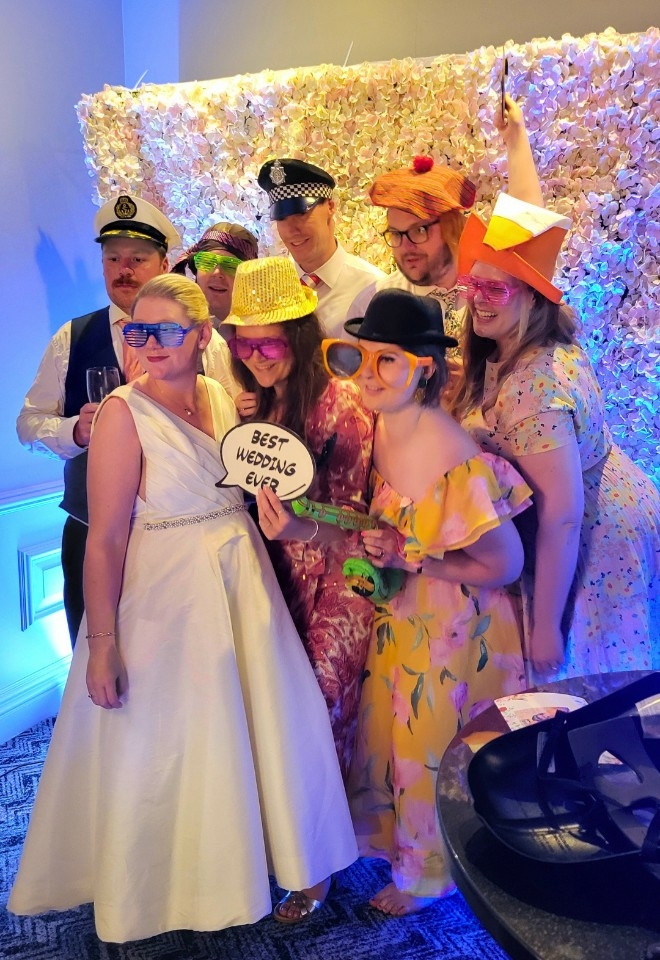 Wedding party in magic mirror photobooth with flower wall backdrop