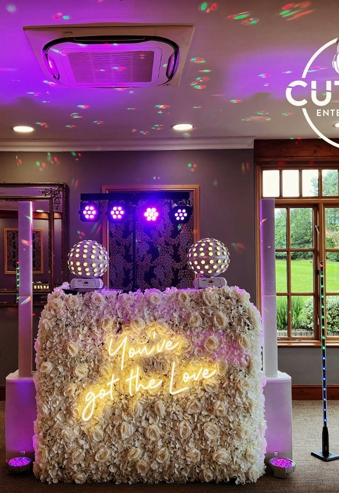 White flower backdrop on DJ stand with neon "Youve got the love" lit up. disco balls and lights for Hintlesham Hall wedding music