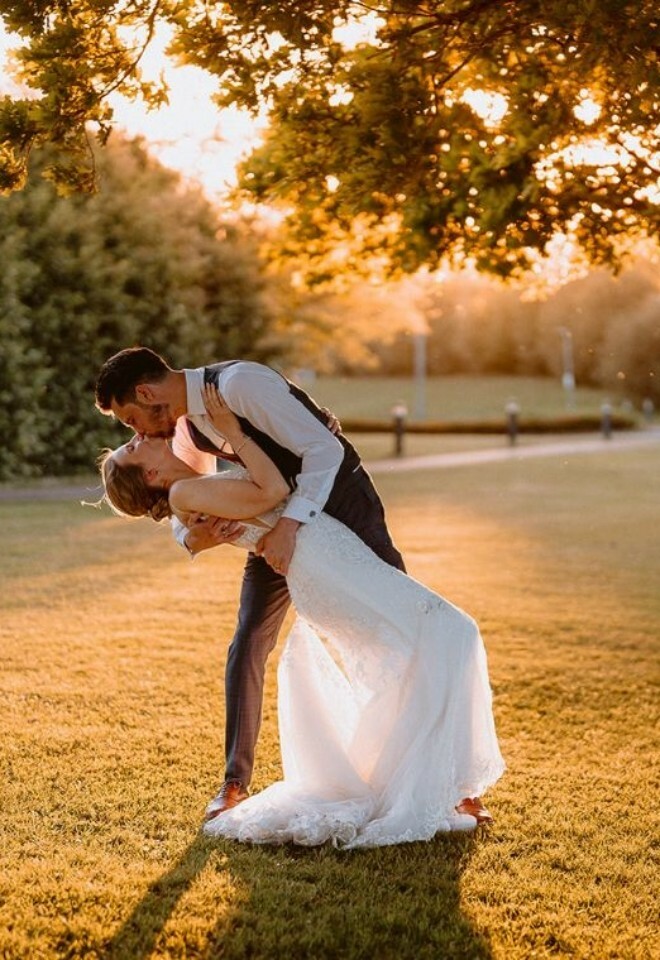 A couple having a photo taken on the lawns in golden hour.