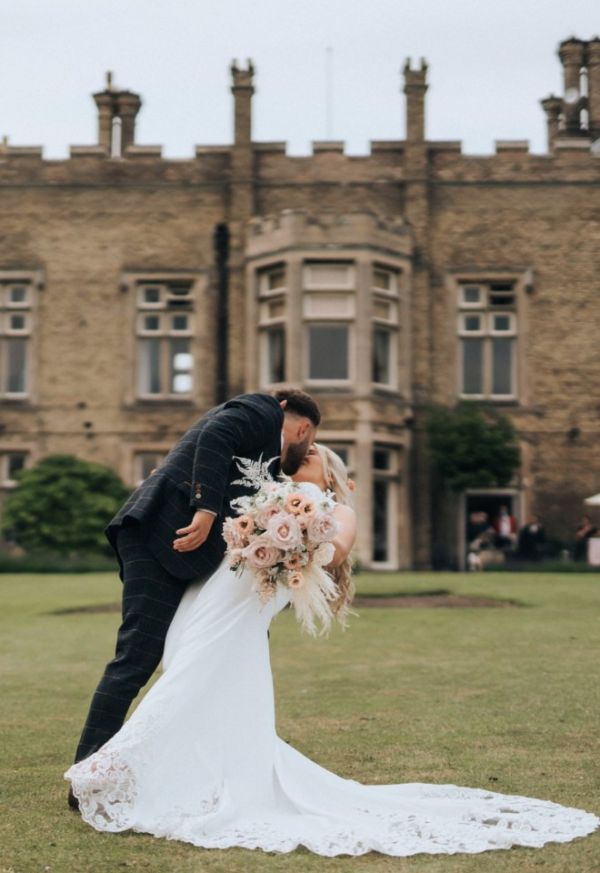 Bride and groom dip kiss on their wedding day. Cave Castle Hotel in the backdrop.