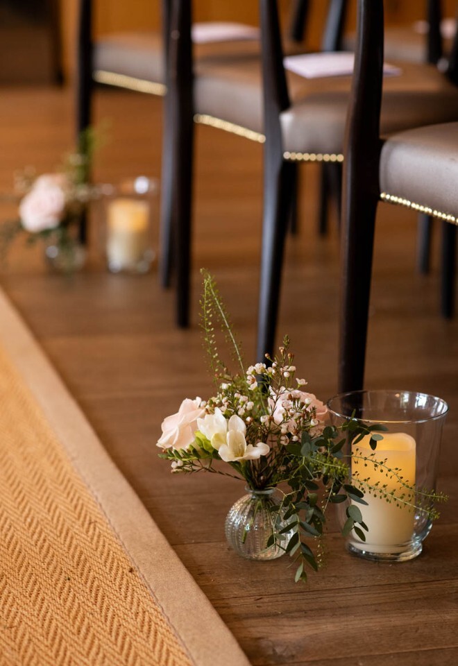 Flowers in bud vases decorate an wedding ceremony aisle.