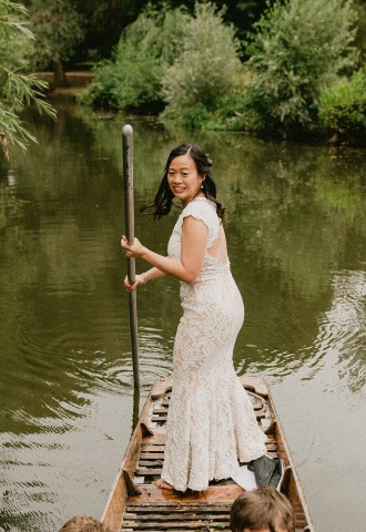 Bride punting along the river Cherwell at her wedding reception, Cherwell Boathouse, Oxfordshire