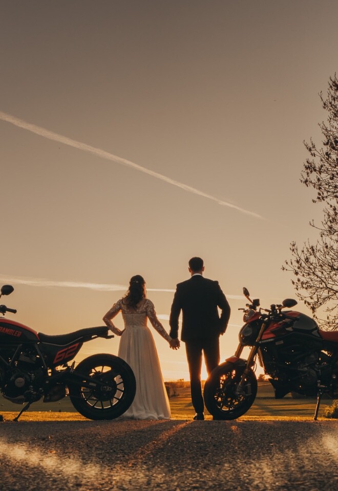 Bride and groom with their motorbikes taking in the sunset at Furtho Manor Farm
