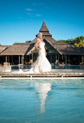 Bride on overseas wedding in Mauritius standing beside swimming pool in wedding dress