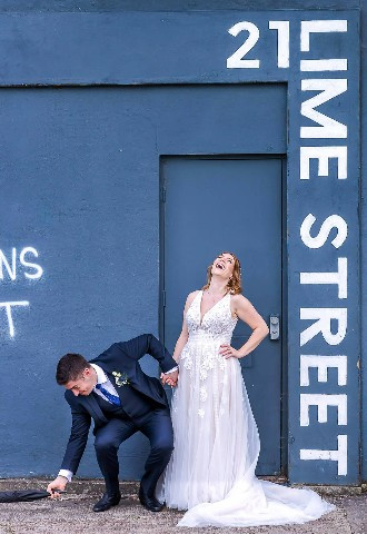 bride laughing after groom drops his umbrella 