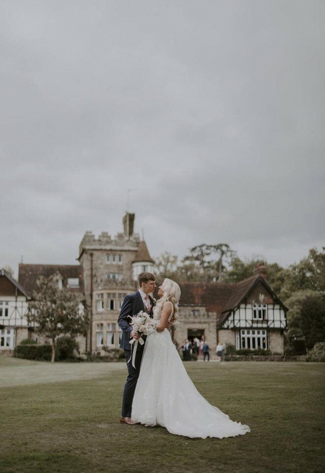 Couple pictured on lawn with the venue as their backdrop