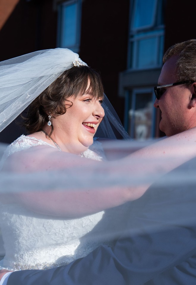 Newlyweds embracing at the Hilton Hotel Leicester, with the brides veil swirling around them