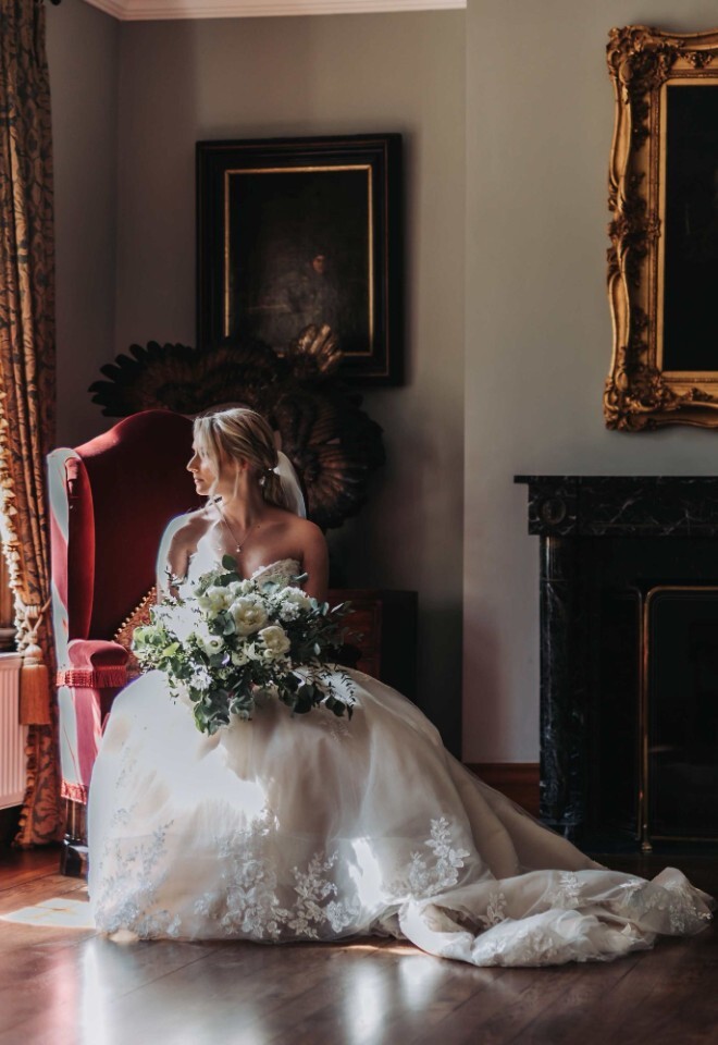The bride and groom standing and sitting in front of a fireplace at a country Northamptonshire wedding venue