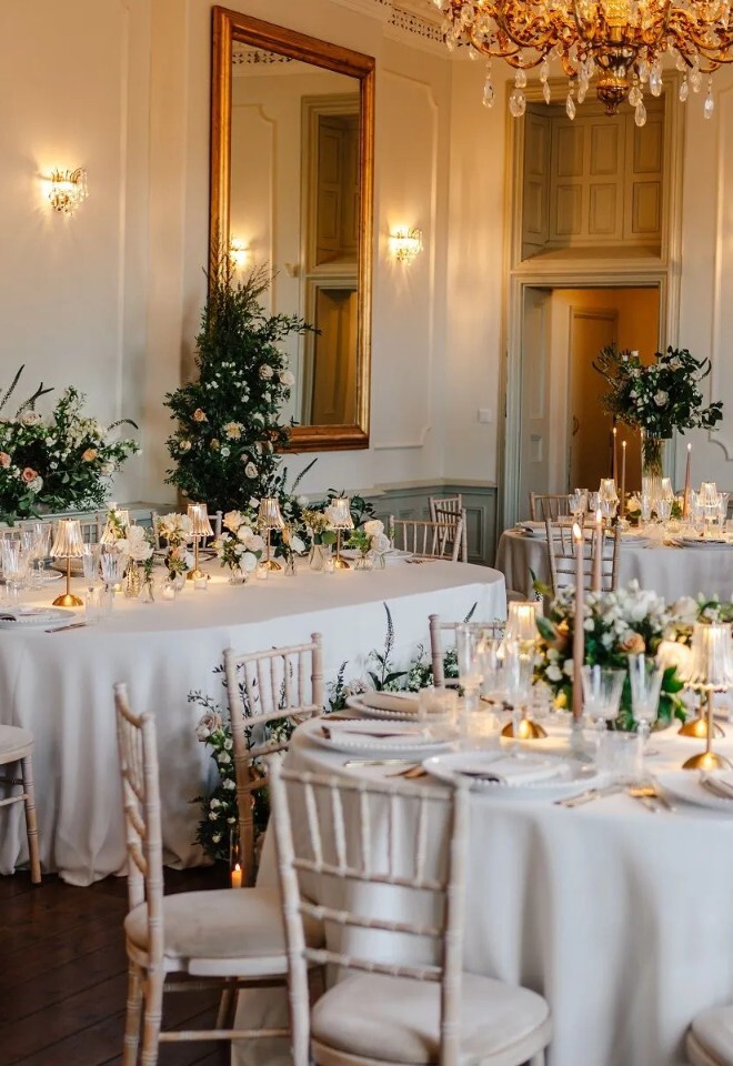 Elegant wedding reception setup at Henlade House wedding venue in Somerset, featuring round tables, floral styling and chandeliers.