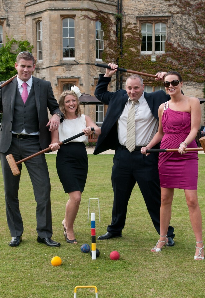 four wedding guests pose with croquet mallets on lawn at weston manor hotel oxfordshire