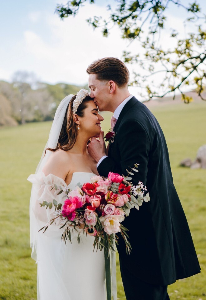 Groom kissing bride on the forehead in front of Chatsworth park at an outdoor wedding venue in Derbyshire (Heathy Lea)