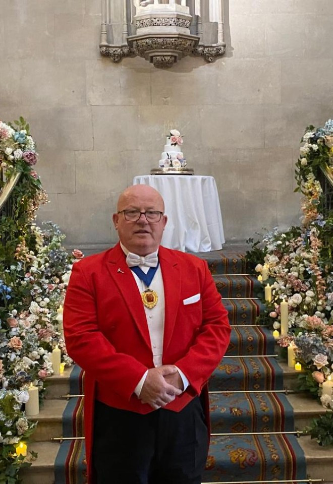 Surrey wedding toastmaster and celebrant Toastmaster John at an elegant wedding venue, surrounded by beautiful floral displays and fairy lights.