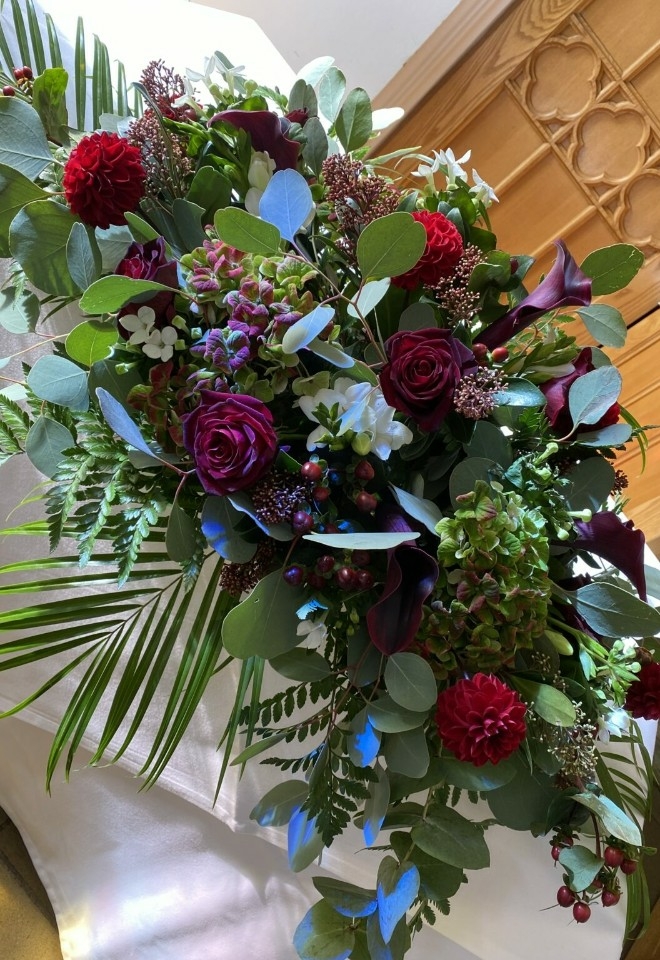 dark red flowers in bouquet on table by hire heaven