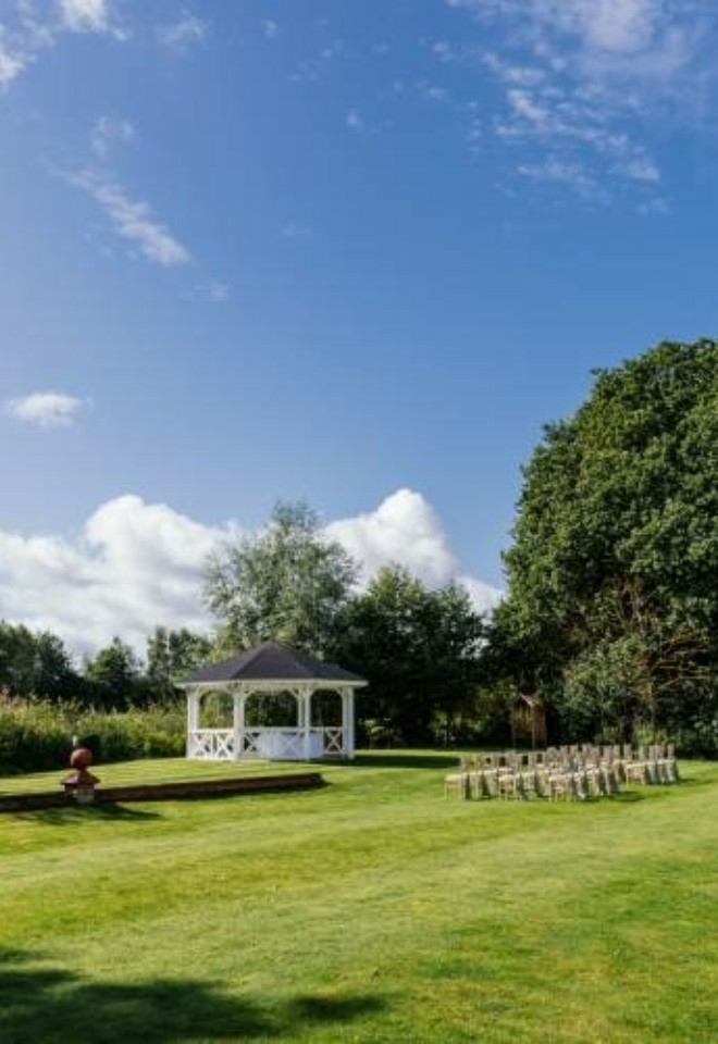 Side view of a ceremony set up outside with the sun shining and blue skies- Sprowston Manor Norwich