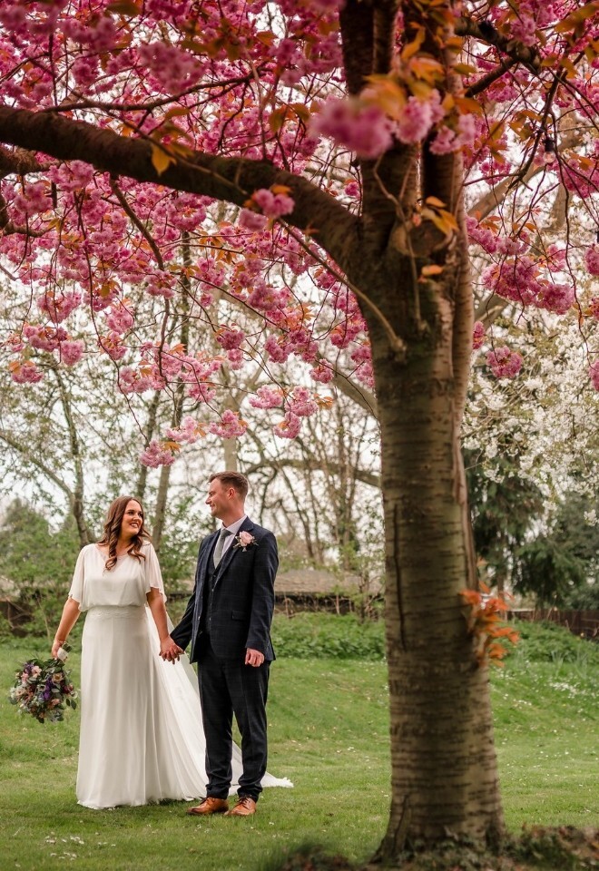 Couple stood under a blossom tree at The Little Fox Wedding Venue in Merseyside