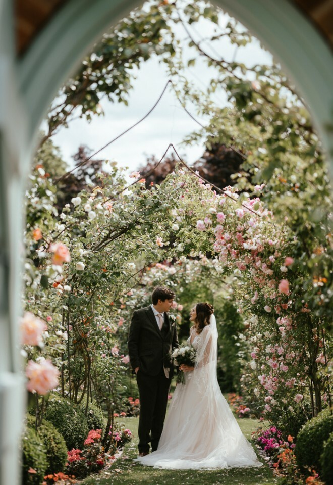 June Wedding in the rose garden, iconic archway door. Roses blossom and greenery