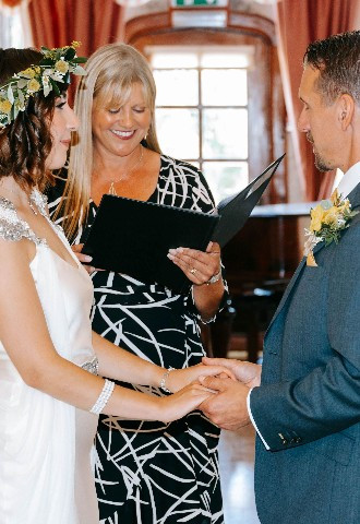 Bride and groom with celebrant Lisa in grand hall at Mount Edgcumbe