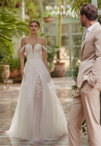 Princess-style A-line wedding dress, crafted in lace with a tulle skirt. Featuring a sweetheart neckline, buttoned back, detachable straps and skirt with a side slit. Lyn by Alma Novia 