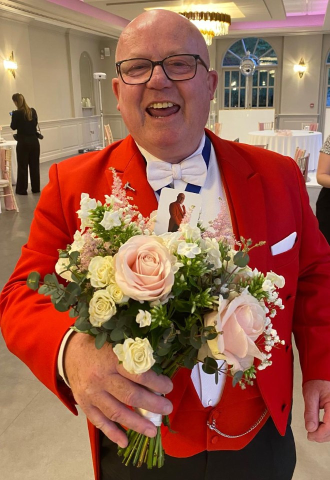 Surrey wedding toastmaster and celebrant Toastmaster John smiling with a bridal bouquet during a wedding celebration.