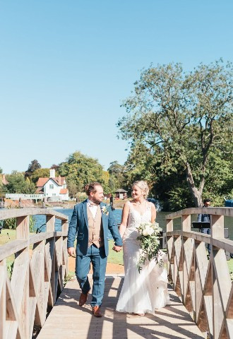 Wedding couple having photo on bridge by river thames at the Swan at Streatley