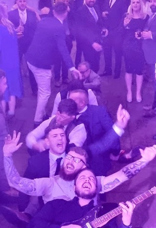 wedding muscians, guitarists sat on the dance floor with wedding guests playing music. best wedding vibes for your evening entertainment