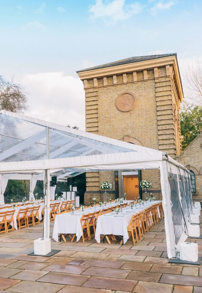 Wedding reception setting in Battersea Park. The tressel tables are beneath a clear marquee