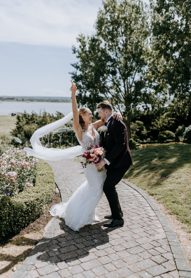 Newlyweds celebrate their wedding with a fun pose overlooking the Kent estuary