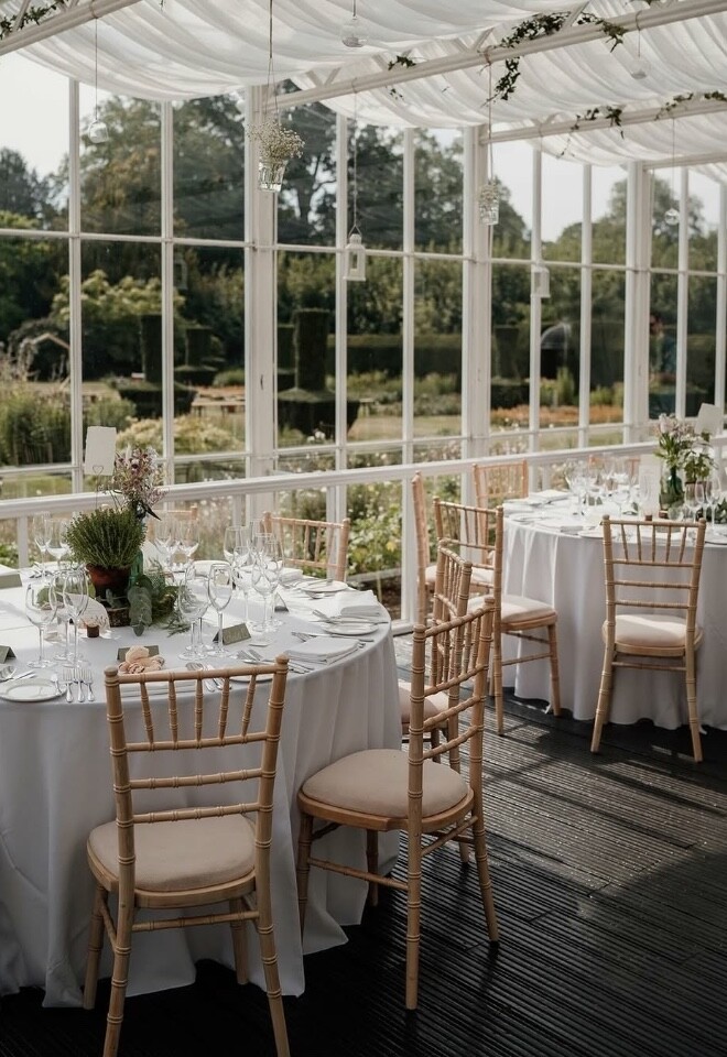 Wedding breakfast set up with round tables inside Sutton Bonington Hall conservatory