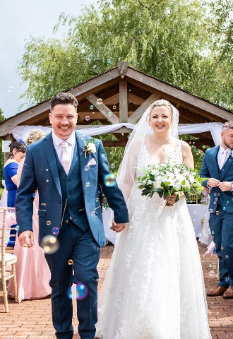 Bride and groom leaving their outdoor wedding ceremony at Reigate Hill Golf Club