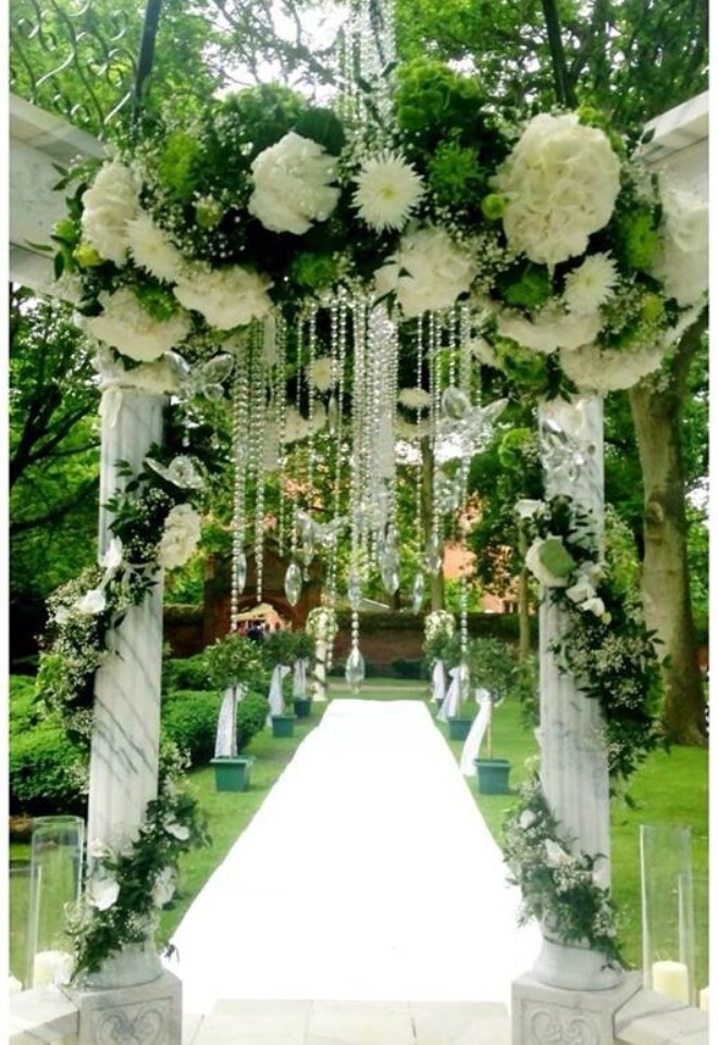 Hanging Halo of Flowers - Creeksea Manor - Essex - The Italian Secret Garden with beautiful white aisle carpet, adorned with pillar foliages and flowers and bay trees