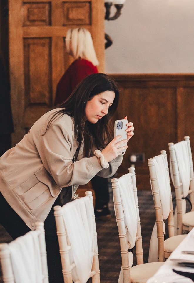 Wedding content creator capturing photos and videos with phone of wedding tablescape