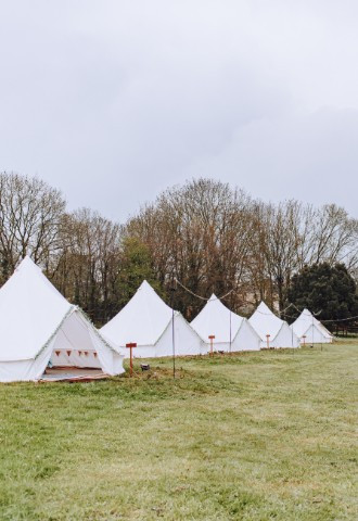 two rows of white bell tents on a glamping site