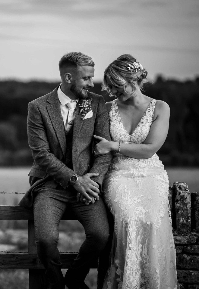 Beautiful black and white of couple sitting on a fence in the Oxfordshire countryside