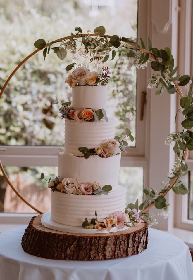 four tier buttercream wedding cake decorated with fresh flowers 