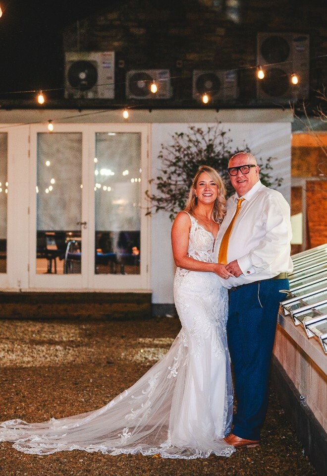 bride and groom on terrace with fairy lights at night
